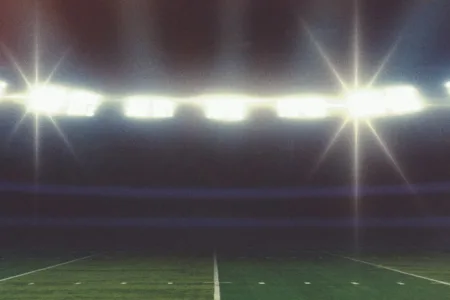 Football stadium lights shining over the field at night